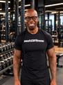 Mandla Mashengele, leende i glasögon och svart mash23fitness-tröja i gymmet